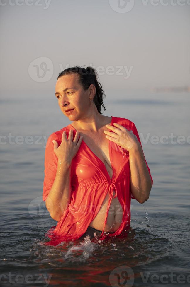 hermosa mayor mujer se baña en el mar y salpicaduras agua. foto