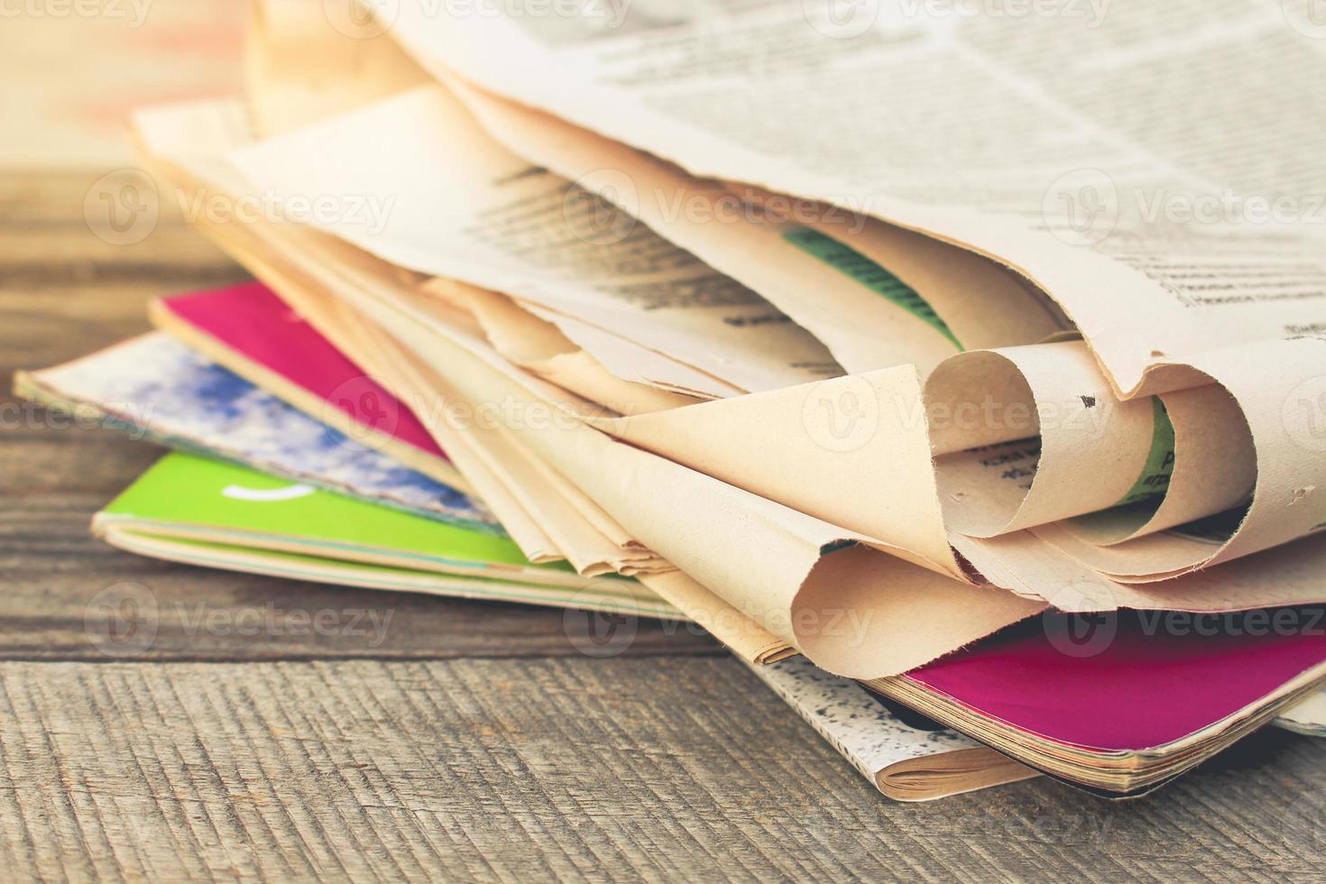 Newspapers and magazines on old wood background. Toned image. photo