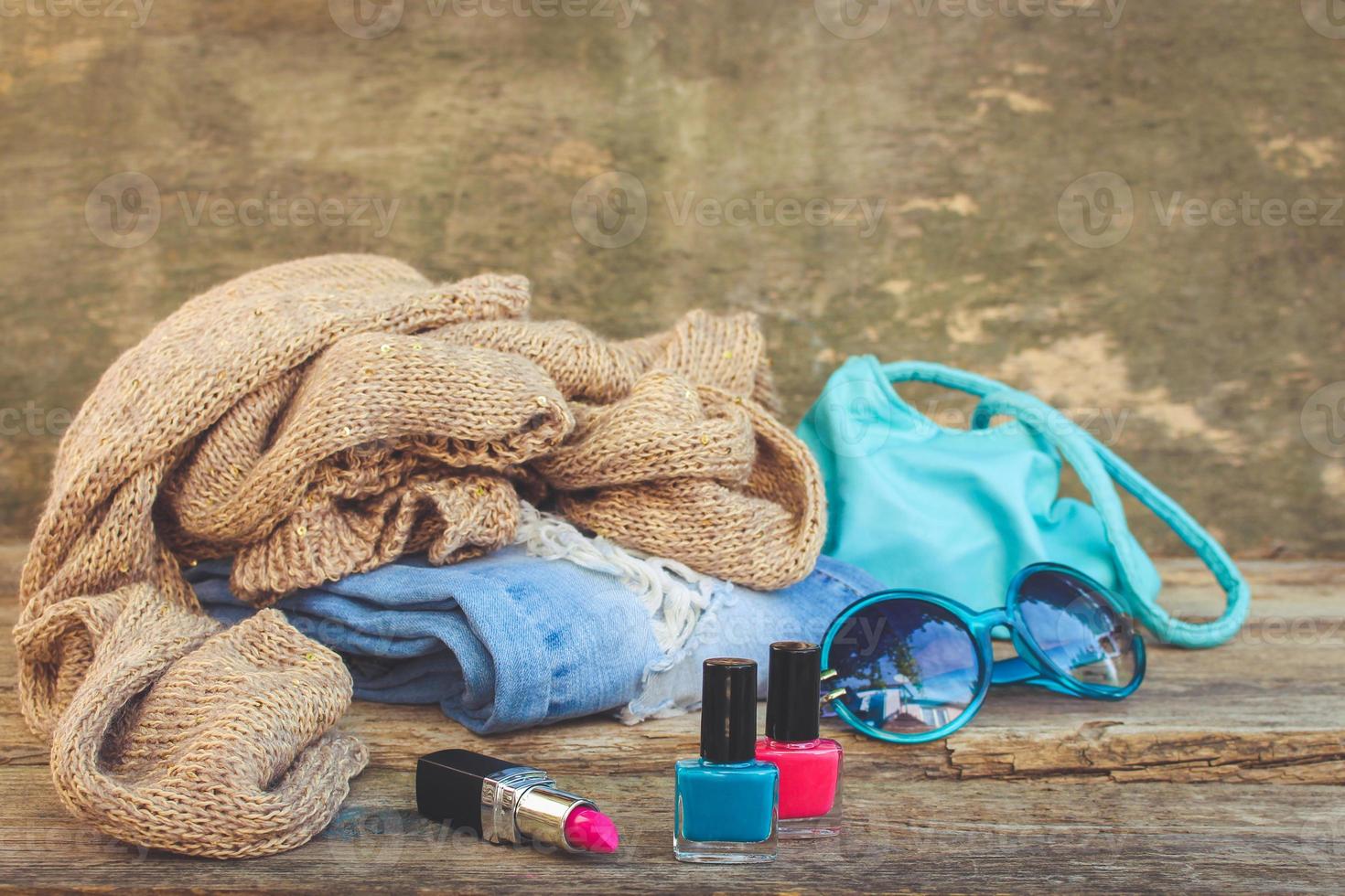 Clothing, women's accessories and cosmetics on old wooden background. Top view. Toned image. photo