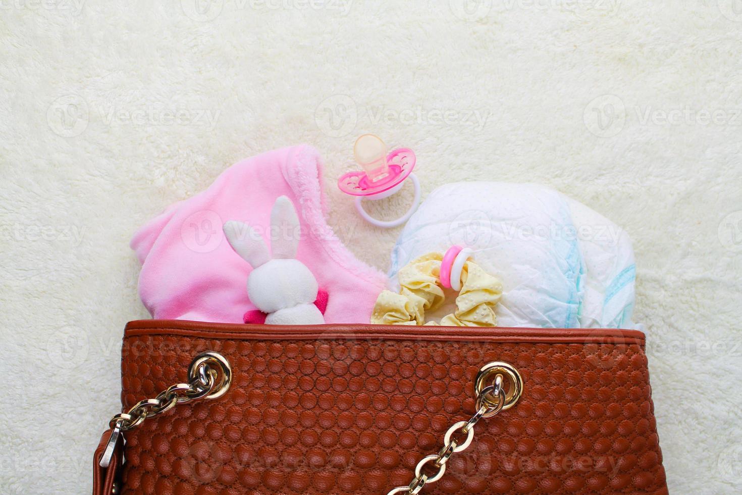 Mother's handbag with items to care for child on white background. Top view. photo