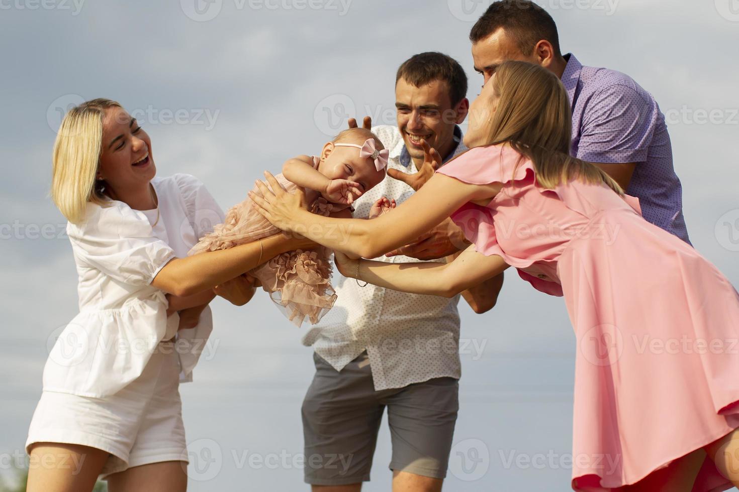 Happy people on a background of blue sky play with a little girl. photo