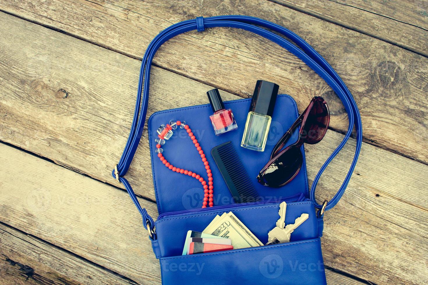 Things from open lady purse. Cosmetics, money and women's accessories fell out of blue handbag. Top view. Toned image. photo