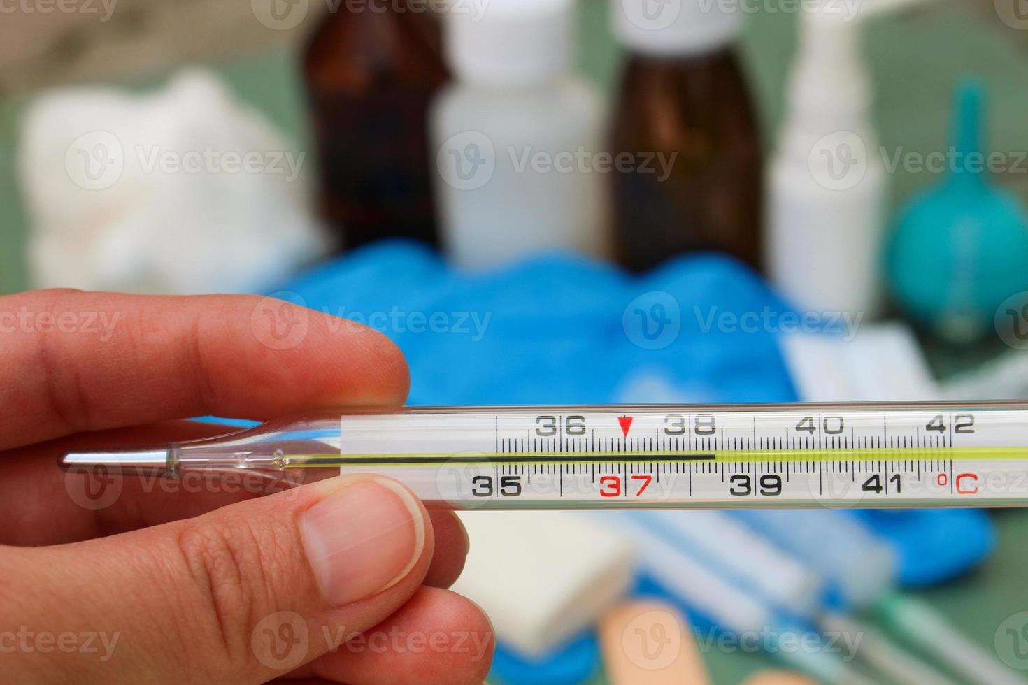 Hand holds thermometer. Body temperature of 38.4 C. photo