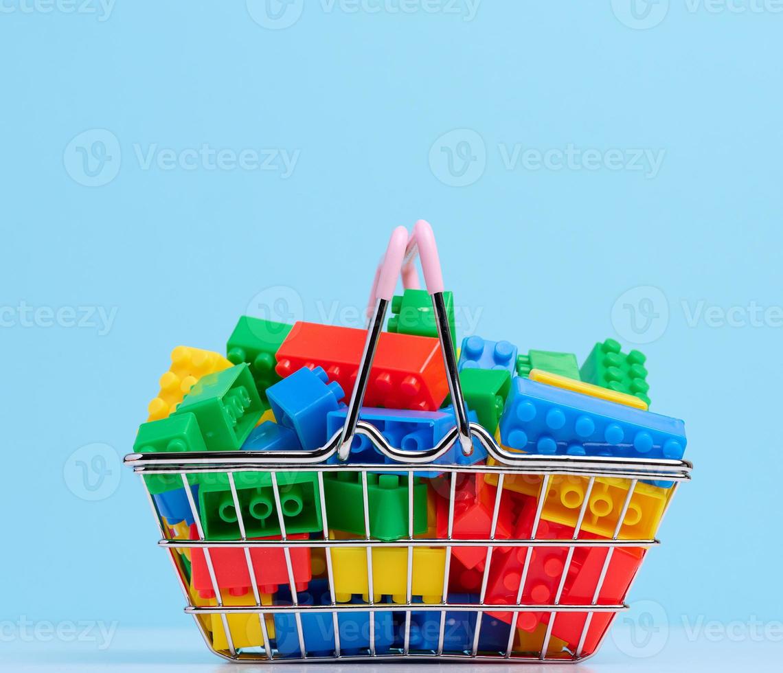Plastic colorful building blocks in a miniature metal shopping cart, educational game for children photo