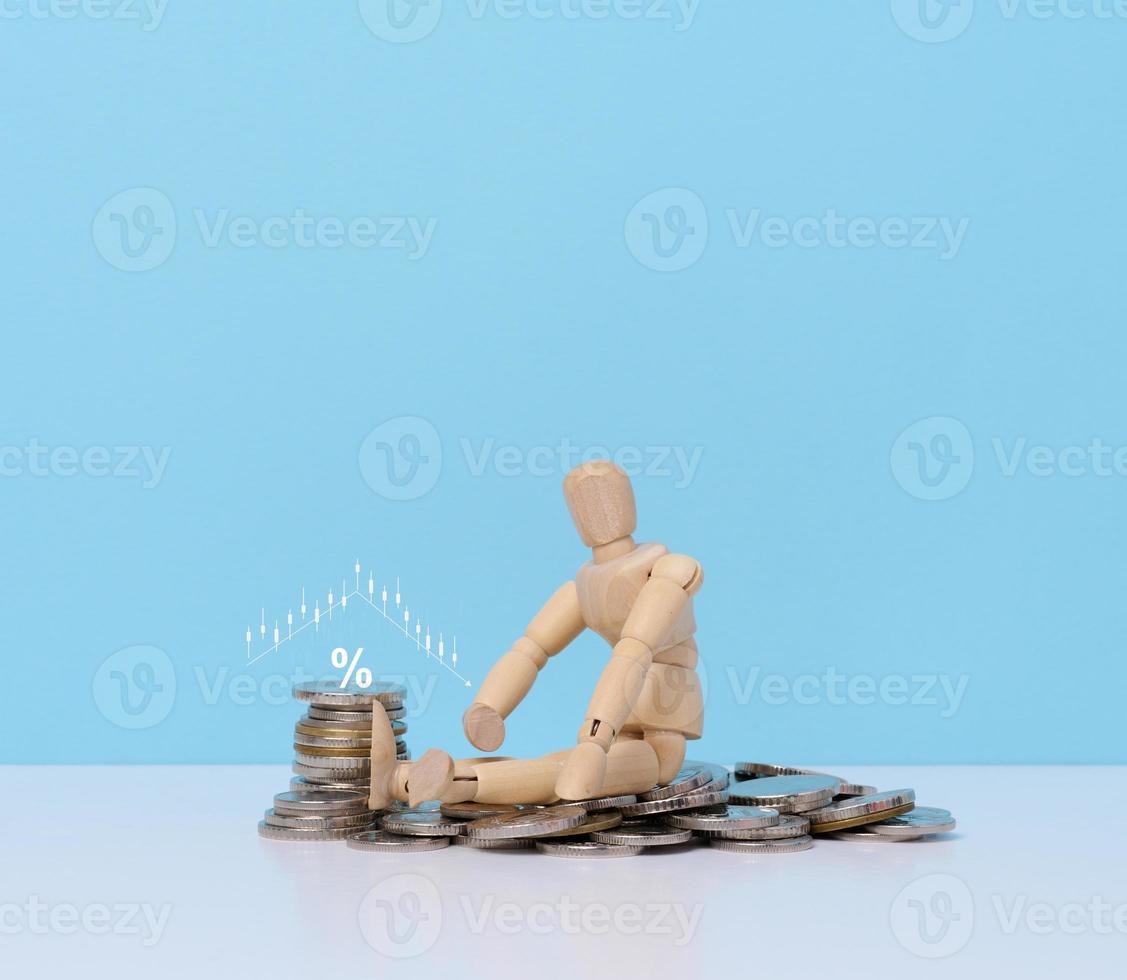 Wooden dummy and a stack of coins, the concept of business collapse, poverty, income decline photo