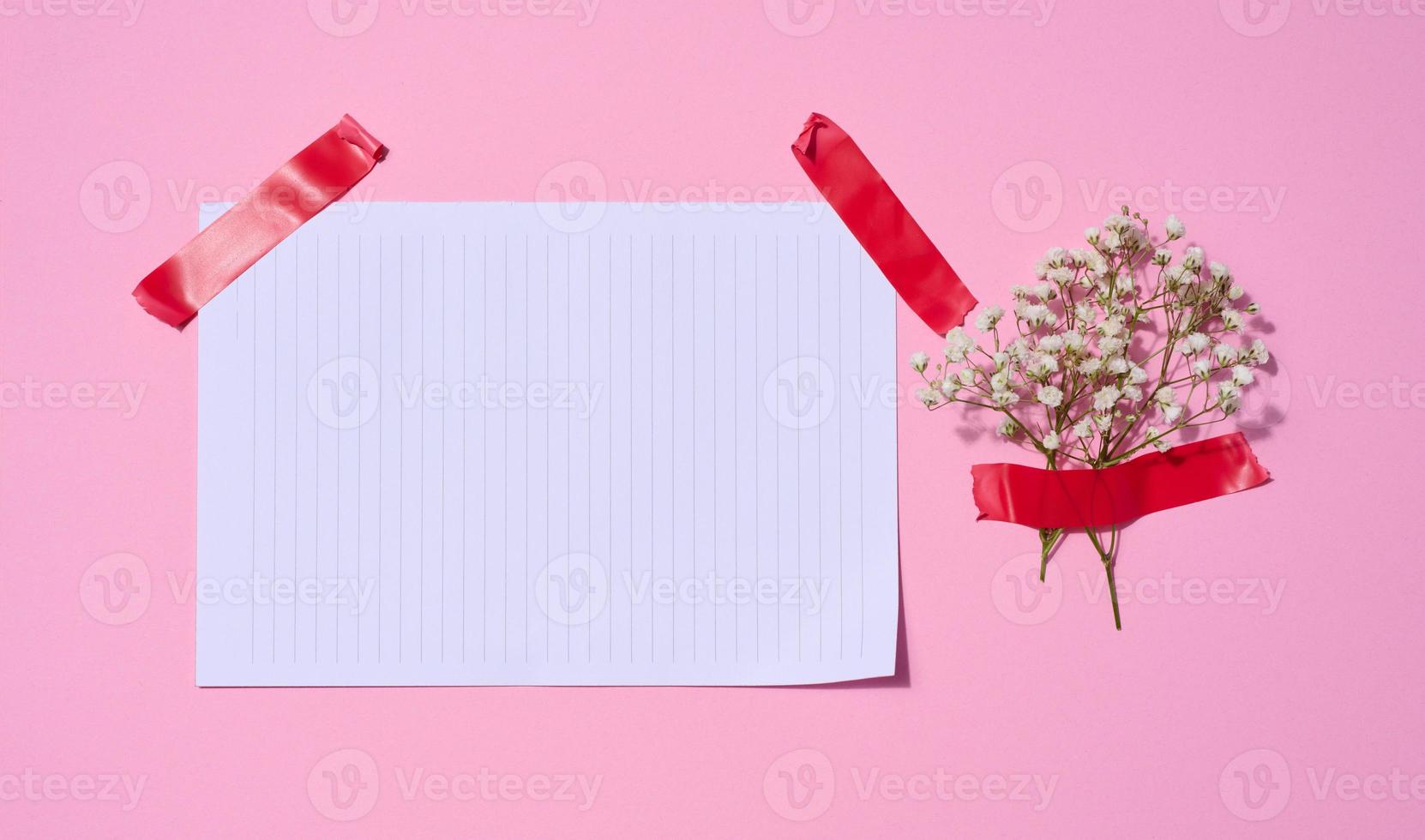 Empty white sheet of paper and gypsophilia flowers on a pink background, space for an inscription photo