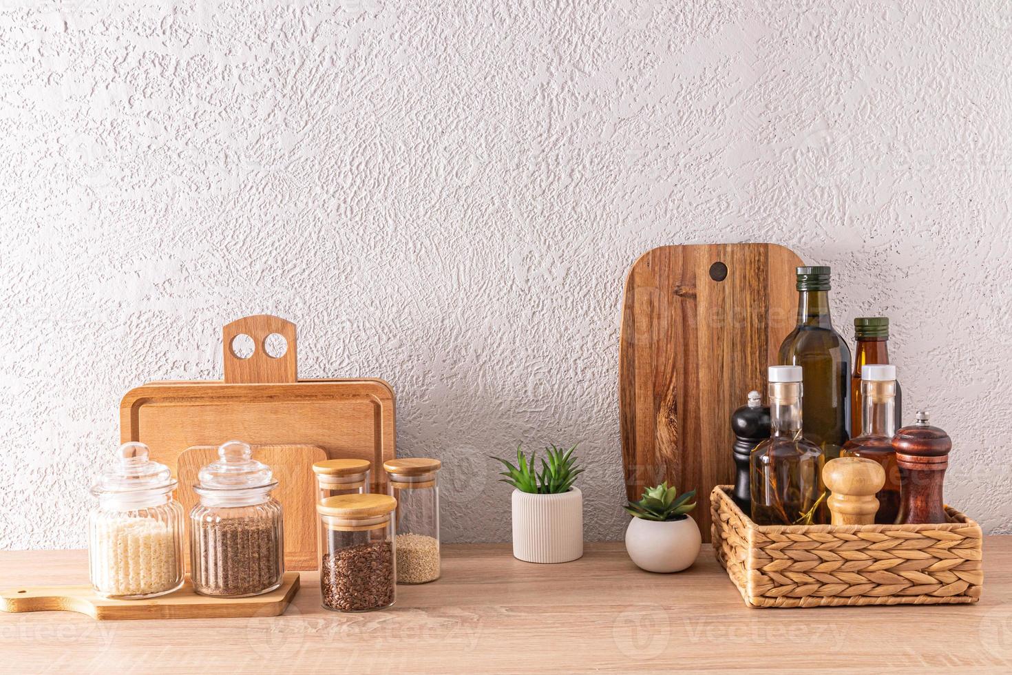 un conjunto de varios cocina utensilios y latas, botellas para comida almacenamiento, de madera corte tableros en un de madera encimera en un moderno cocina. foto