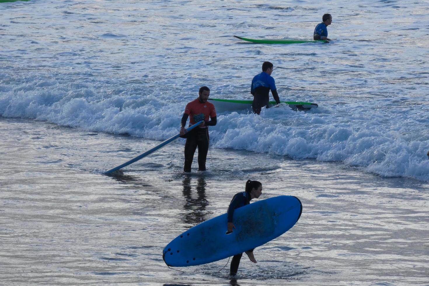 Surfers getting ready to enter the water and walking with the board along the shore. photo