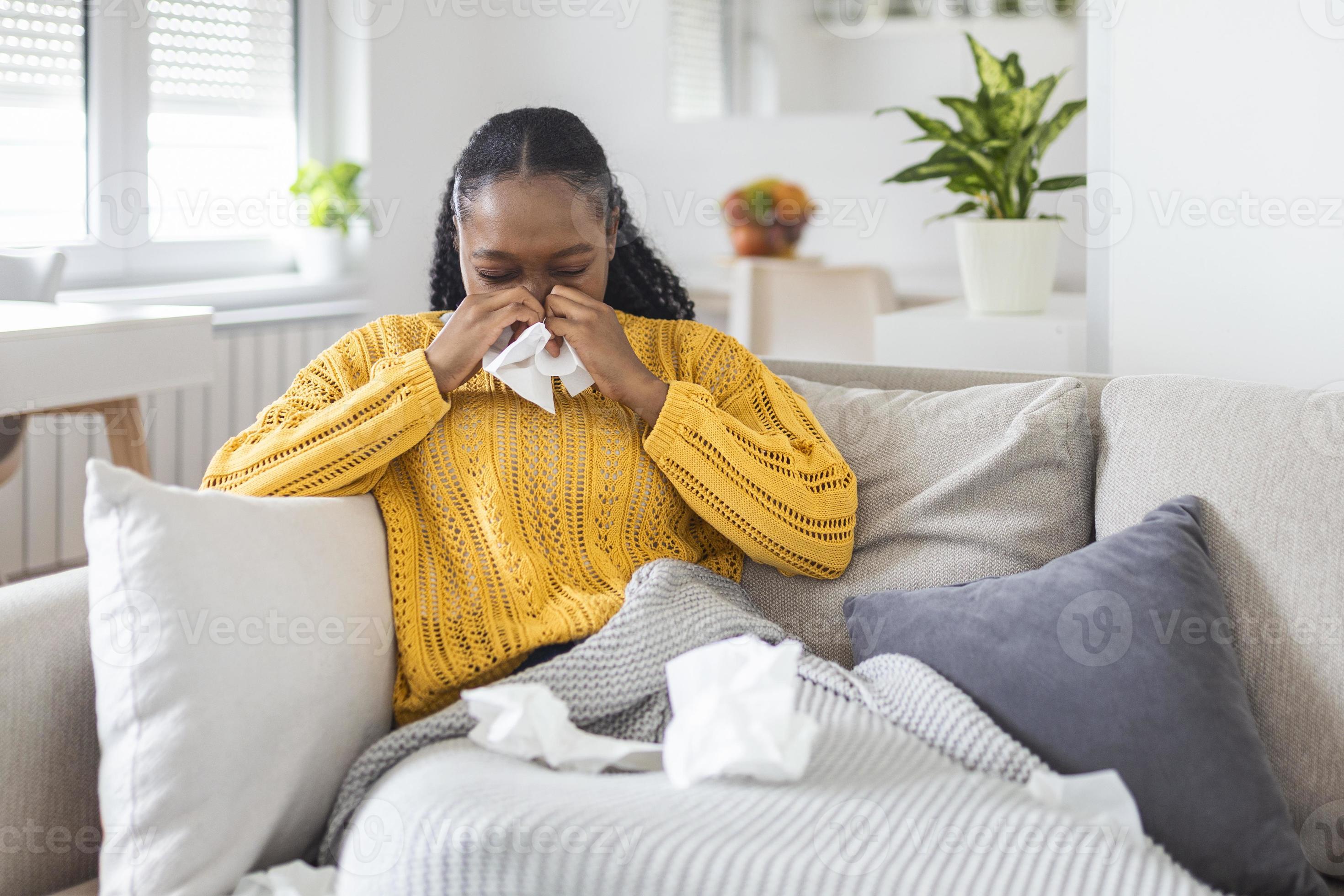 Sick young african woman feeling cold covered with blanket sit on bed