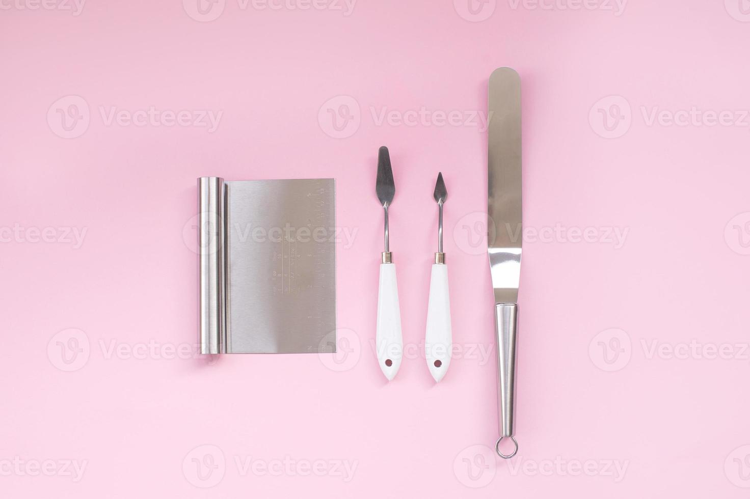 Metal pastry chef's tools on a pink background. Spatulas and spatulas for making cake photo
