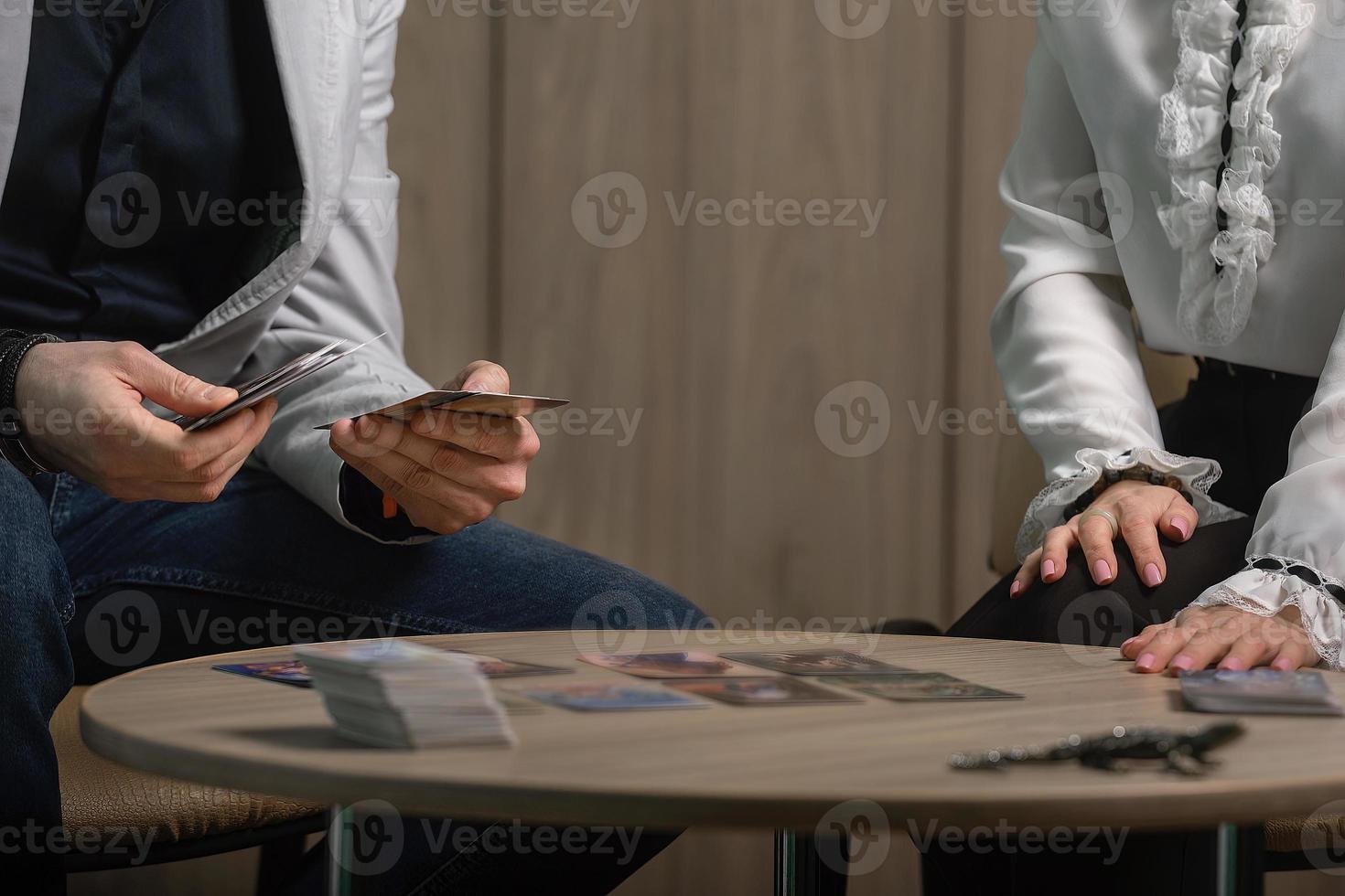 A male psychologist, a specialist in metaphorical, associative MAC cards, is receiving a client, a young woman. Signs of the Universe, signs and answers to questions. photo