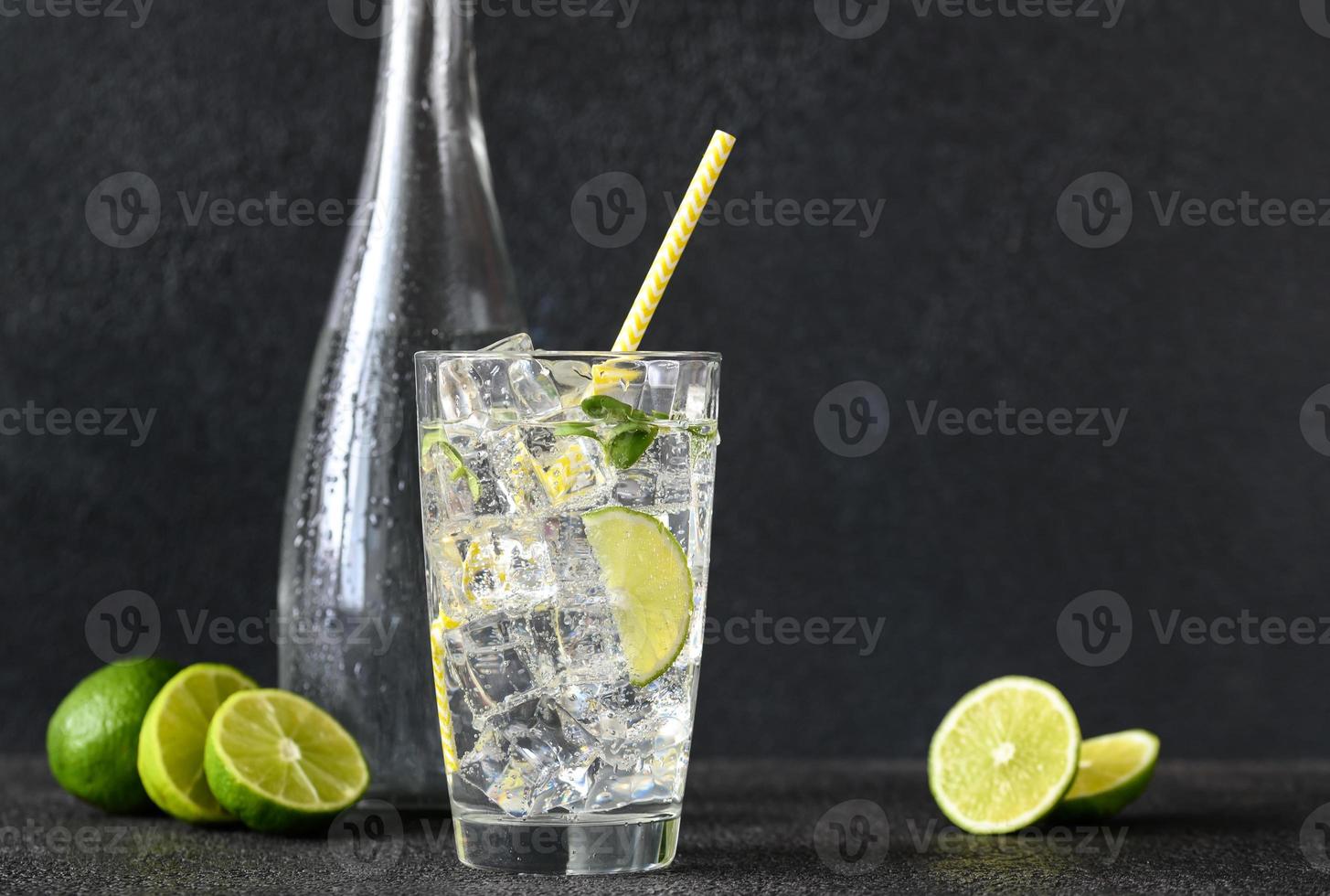 Glass of sparkling water with ice cubes and slice of lime photo