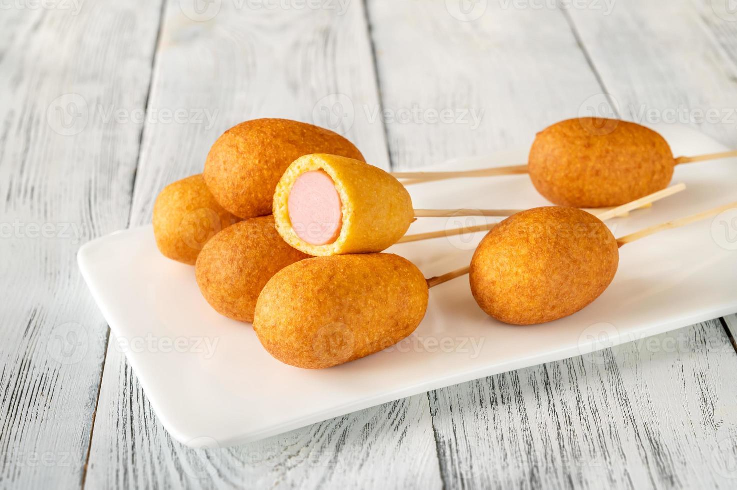 Corn dogs on white serving plate photo