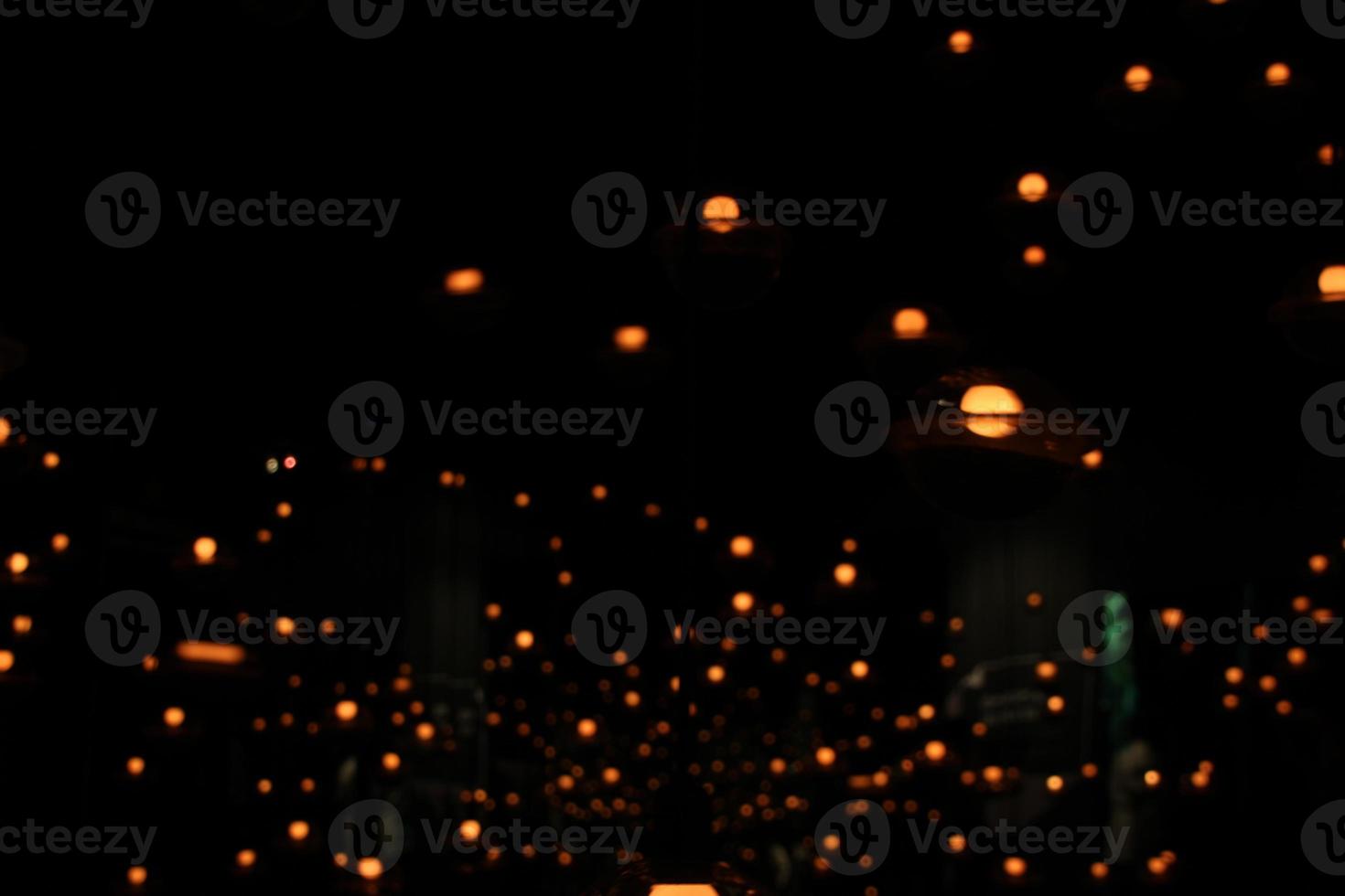 blur bokeh circus tube lamp hang from ceiling in black dark room like firefly photo