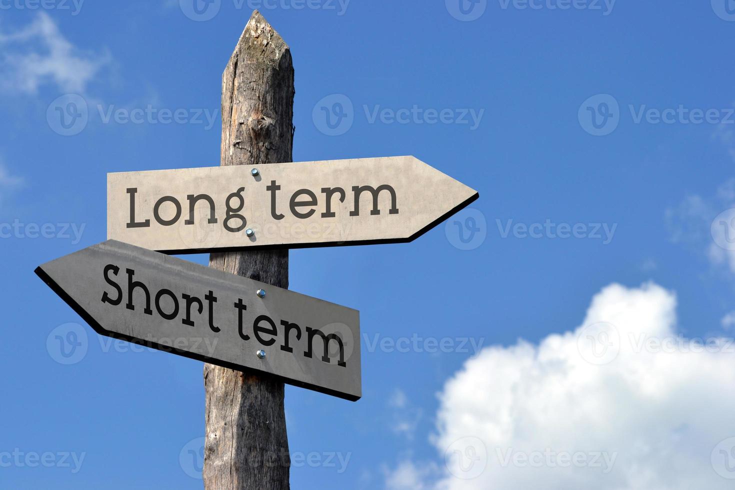 Short or Long Term - Wooden Signpost with Two Arrows, Sky with Clouds photo