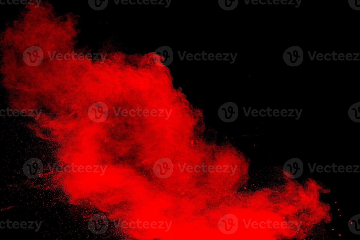 Red powder explosion cloud on black background. Freeze motion of red color dust  particles splashing. photo