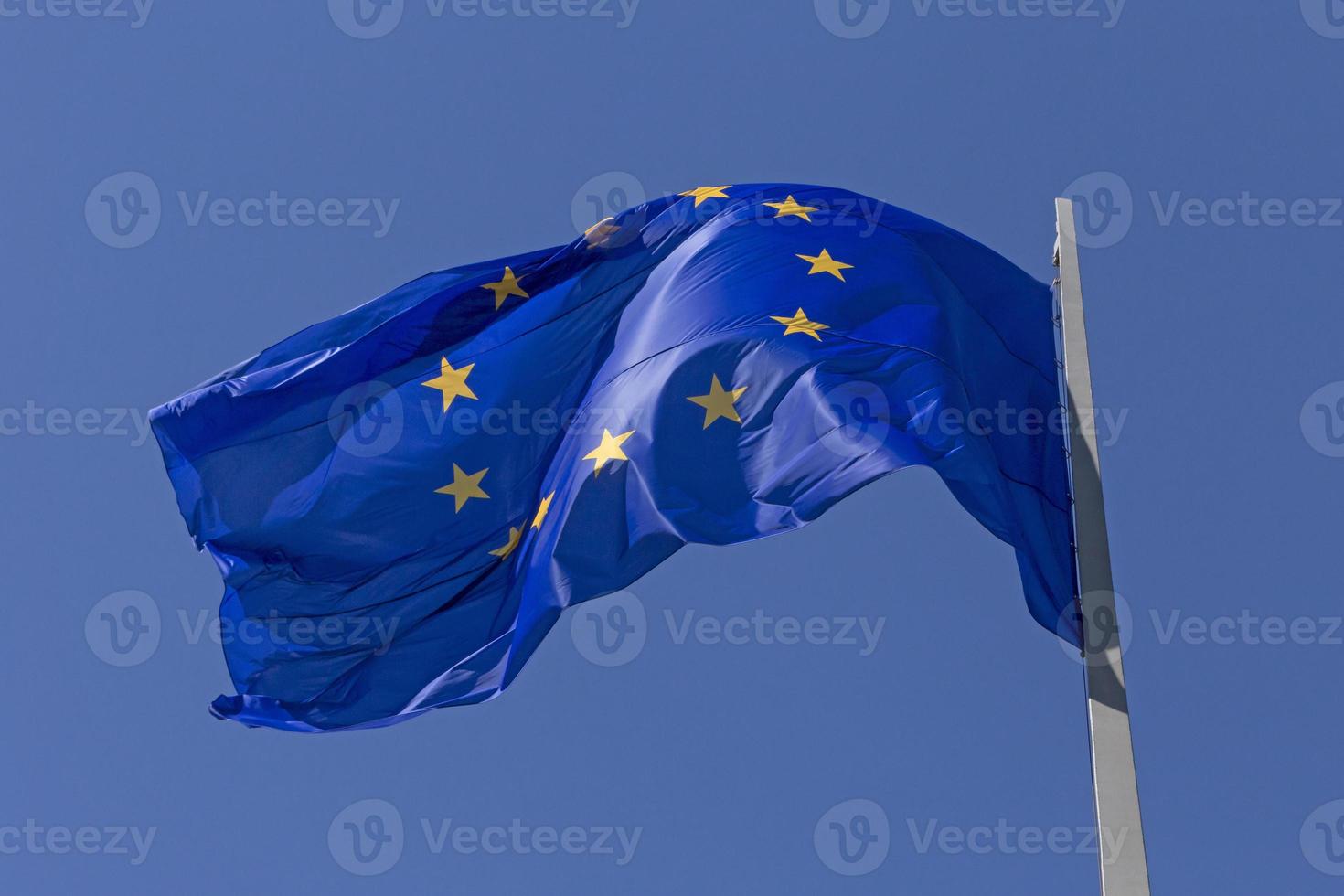 waved European Union flag on flagpole against blue sky photo