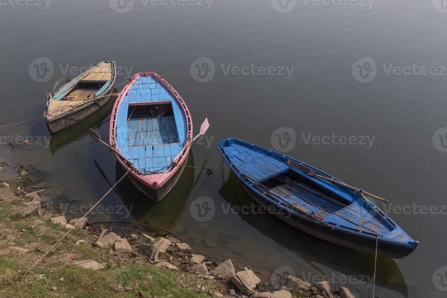 Tres barcos a costa de ganges río en varanasi ciudad foto