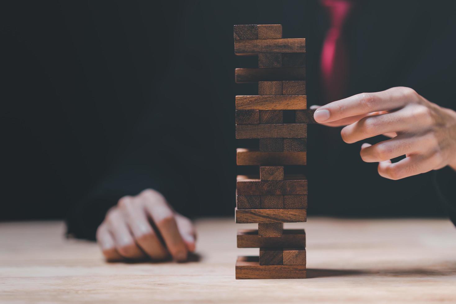 Businessman pulling a jenga wooden box ,protection and risk management ,Financial risk management ,protection of business interests ,business risk analysis ,Decisions on Business Opportunities photo