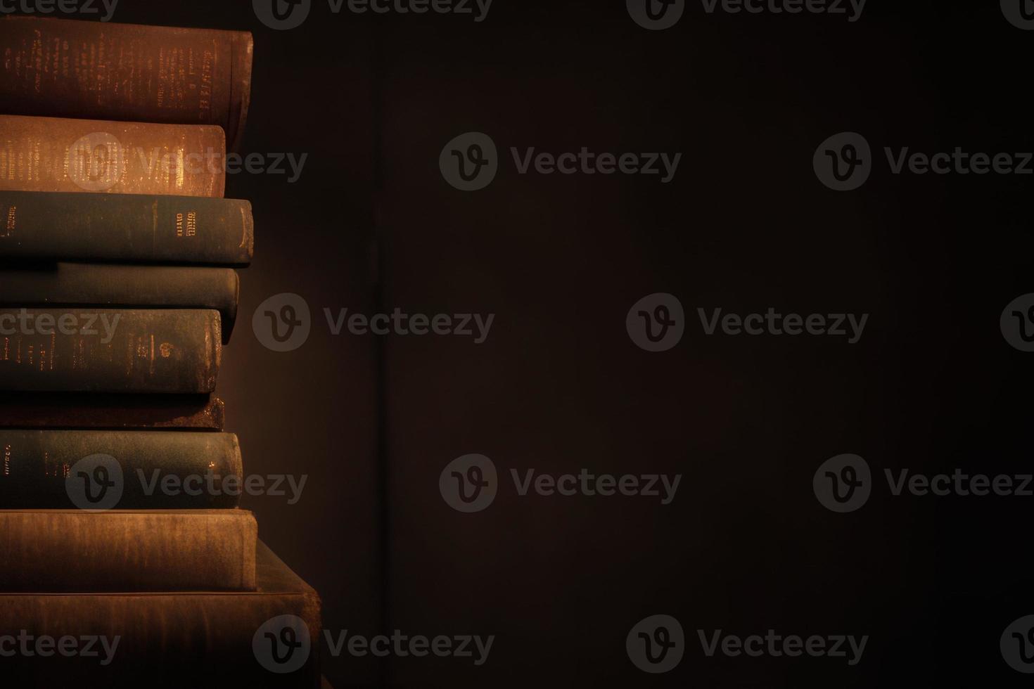 dark brown old book stack in the dark room with copy space background photo