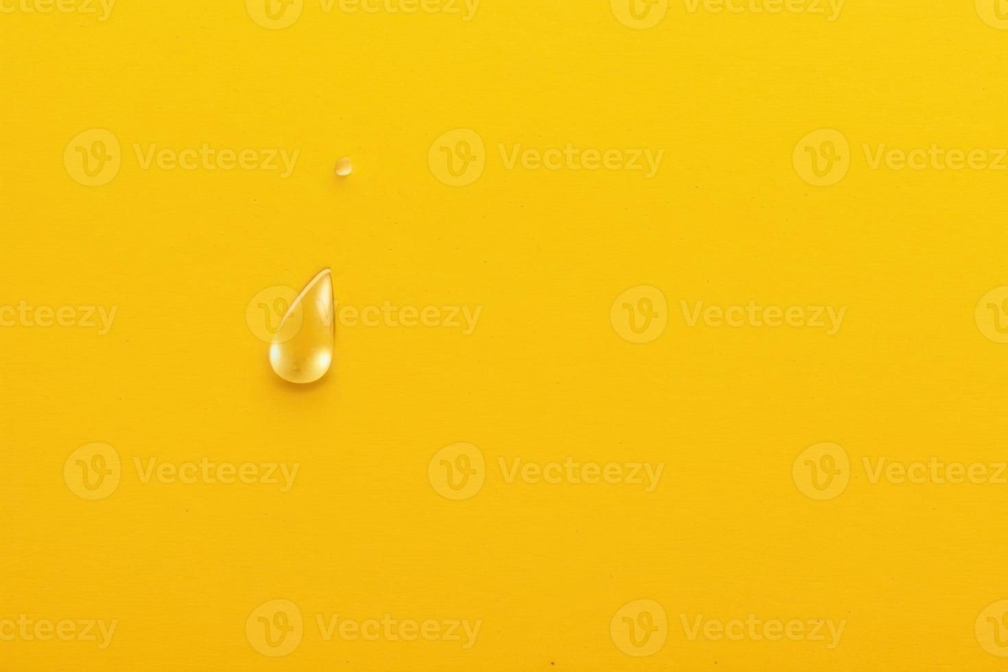 single water drop on yellow plain background, minimalistic design backdrop with copy space photo