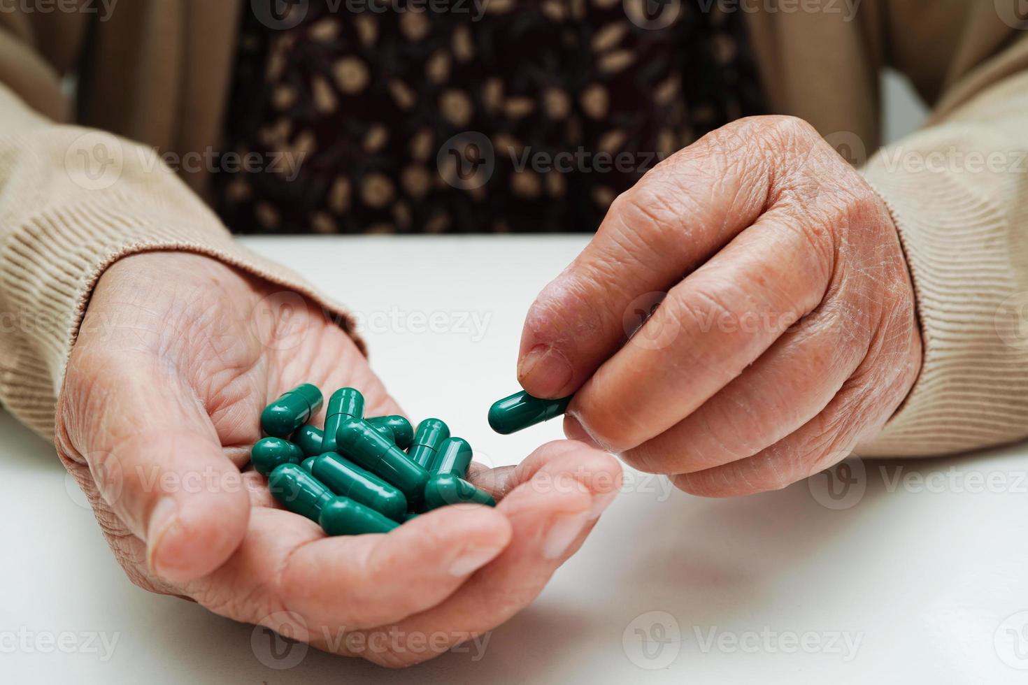 anciana asiática con píldora en la mano, fuerte concepto médico saludable. foto