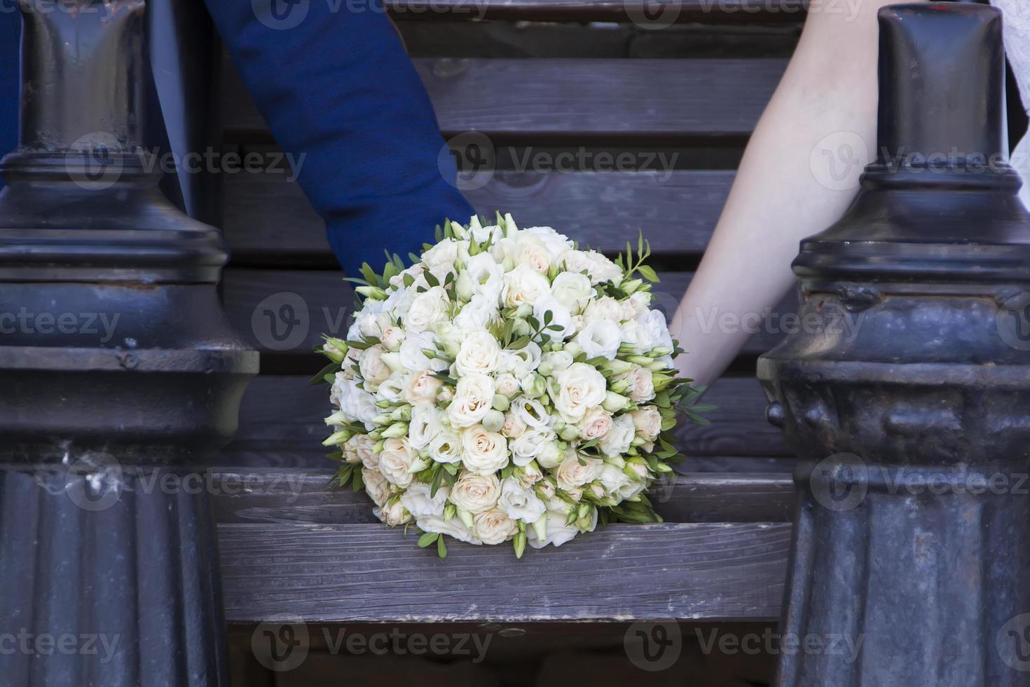 Hands of the bride and groom are holding a wedding bouquet. photo