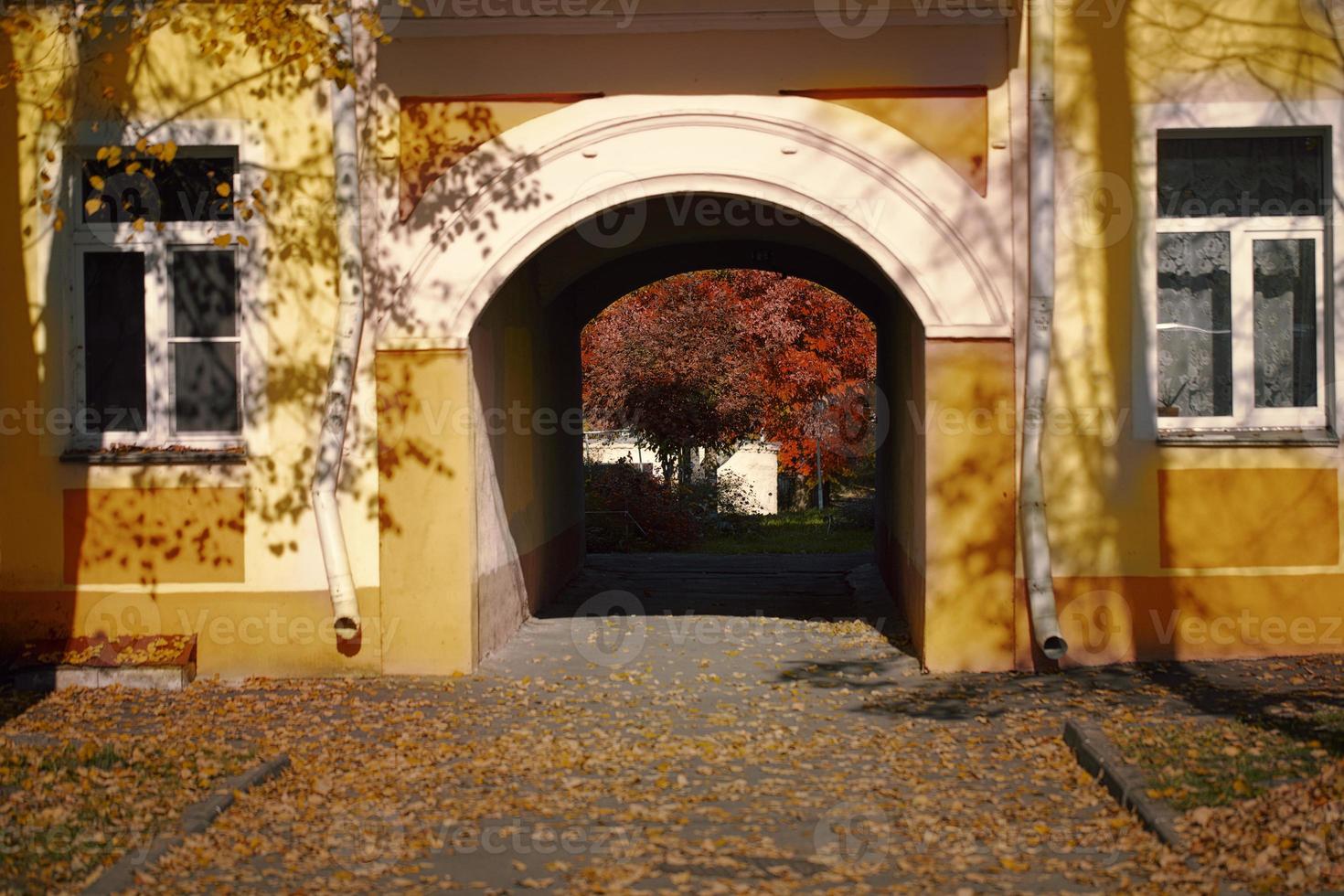 An arch in an old yellow house and two windows. photo