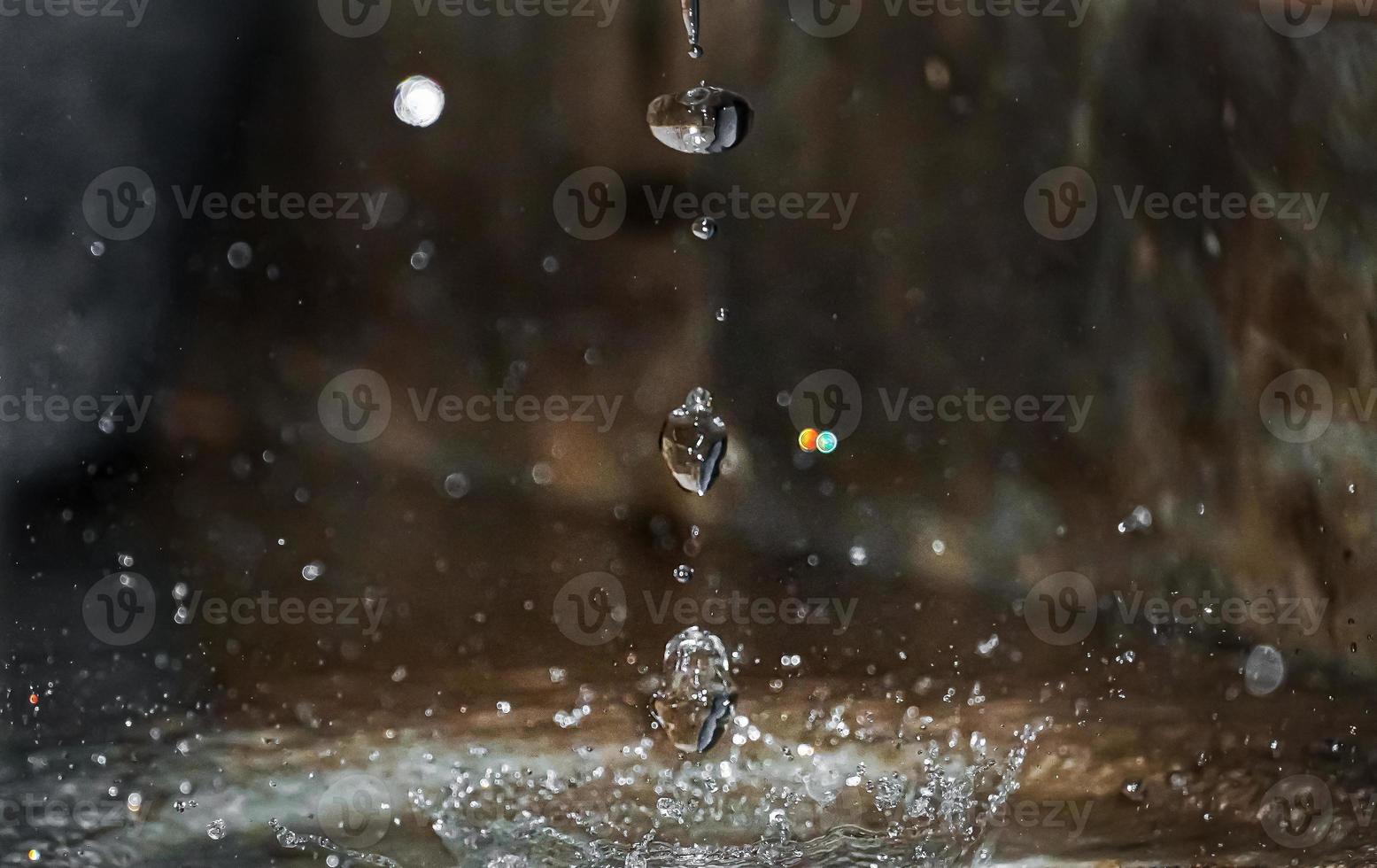 Round rain drops falling on smooth surface of water. photo