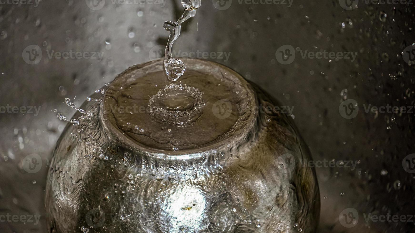 Round rain drops falling on smooth surface of water photo