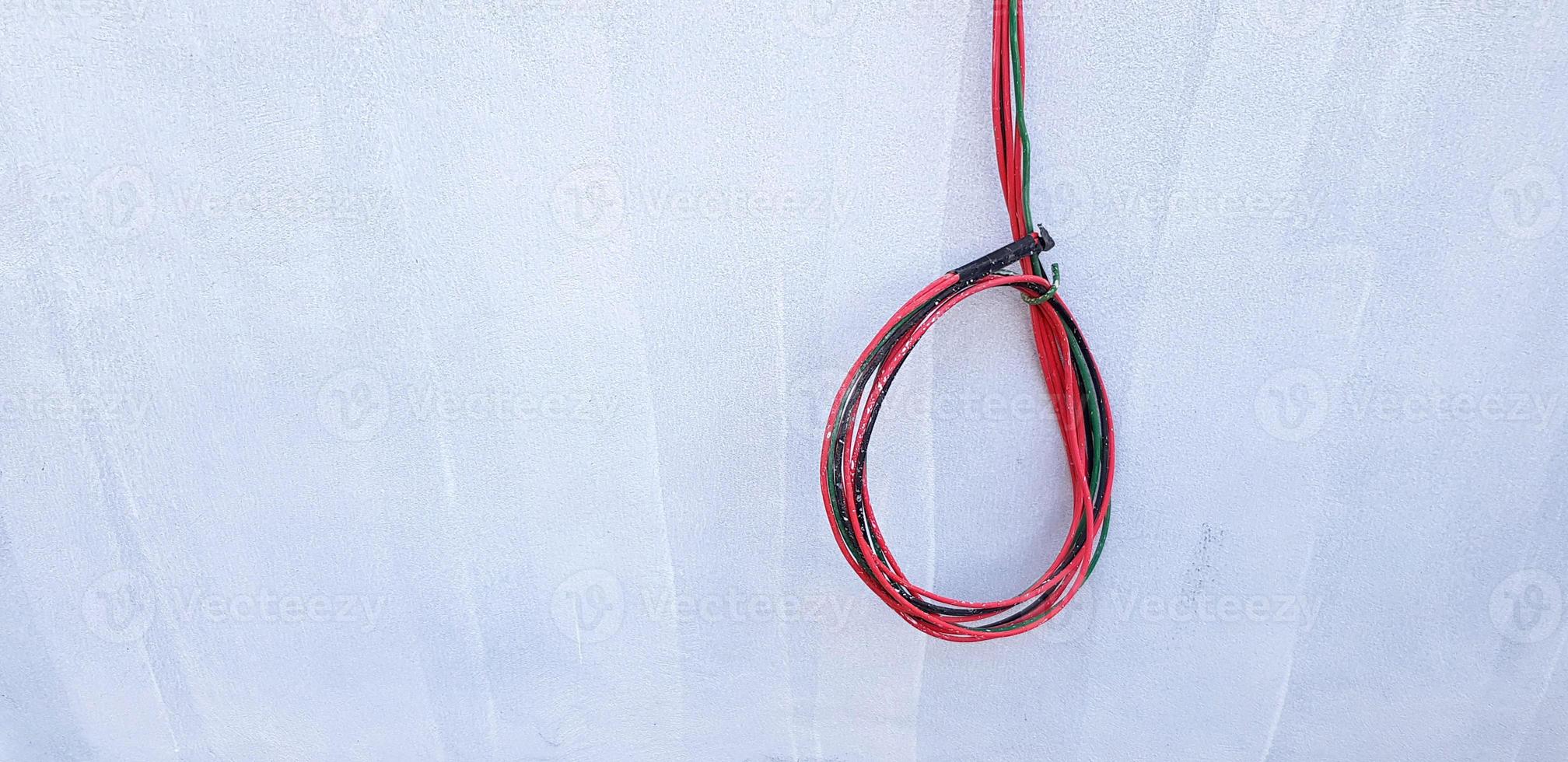 Red, Black, and Green cable hanging or isolated on gray concrete wall with copy space. New installation wiring power cord, Connection, Repair building and Electrical system industrial concept photo