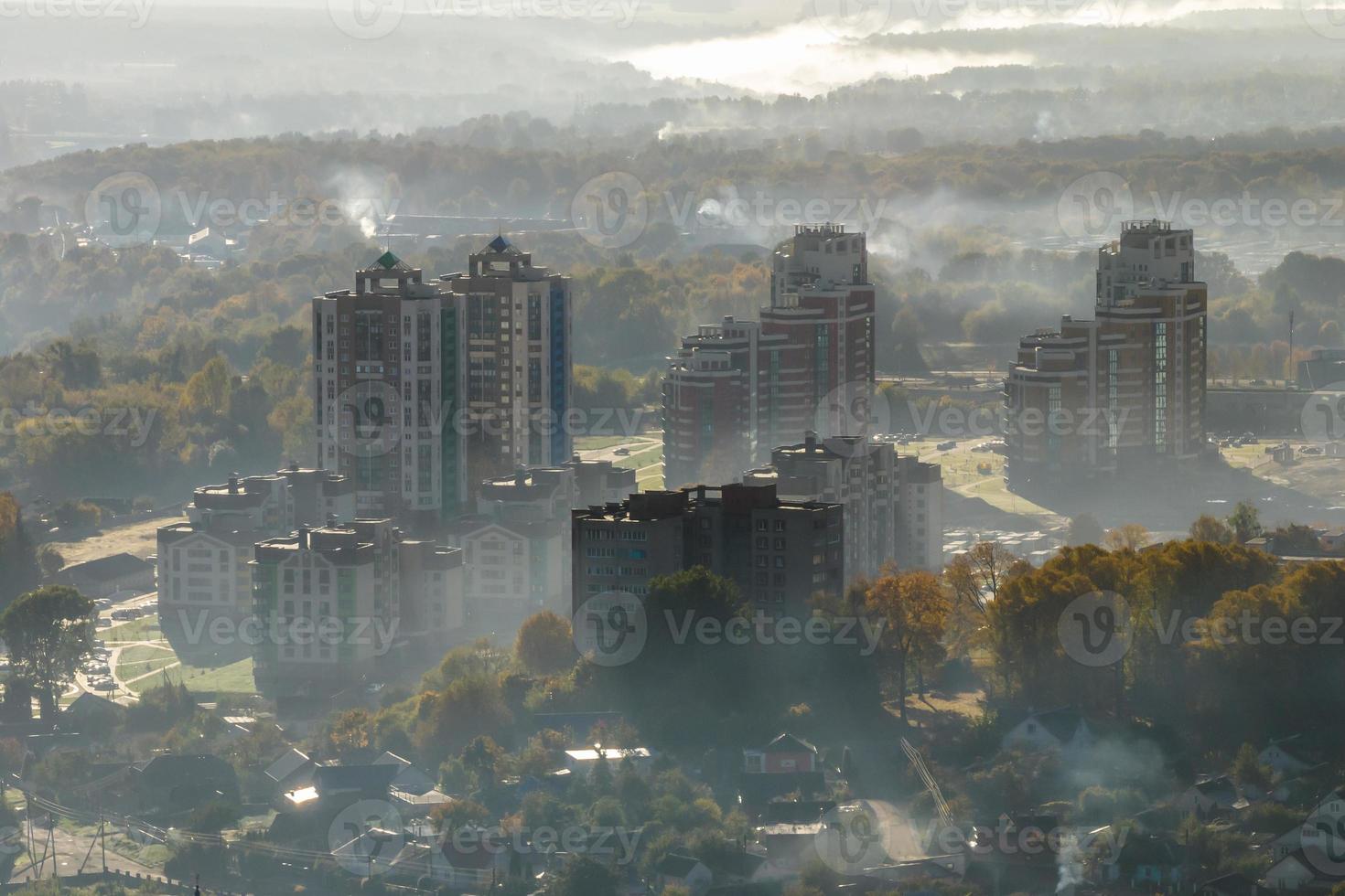 aerial view of green city with skysrapers and residential buildings in earning fog and mist photo