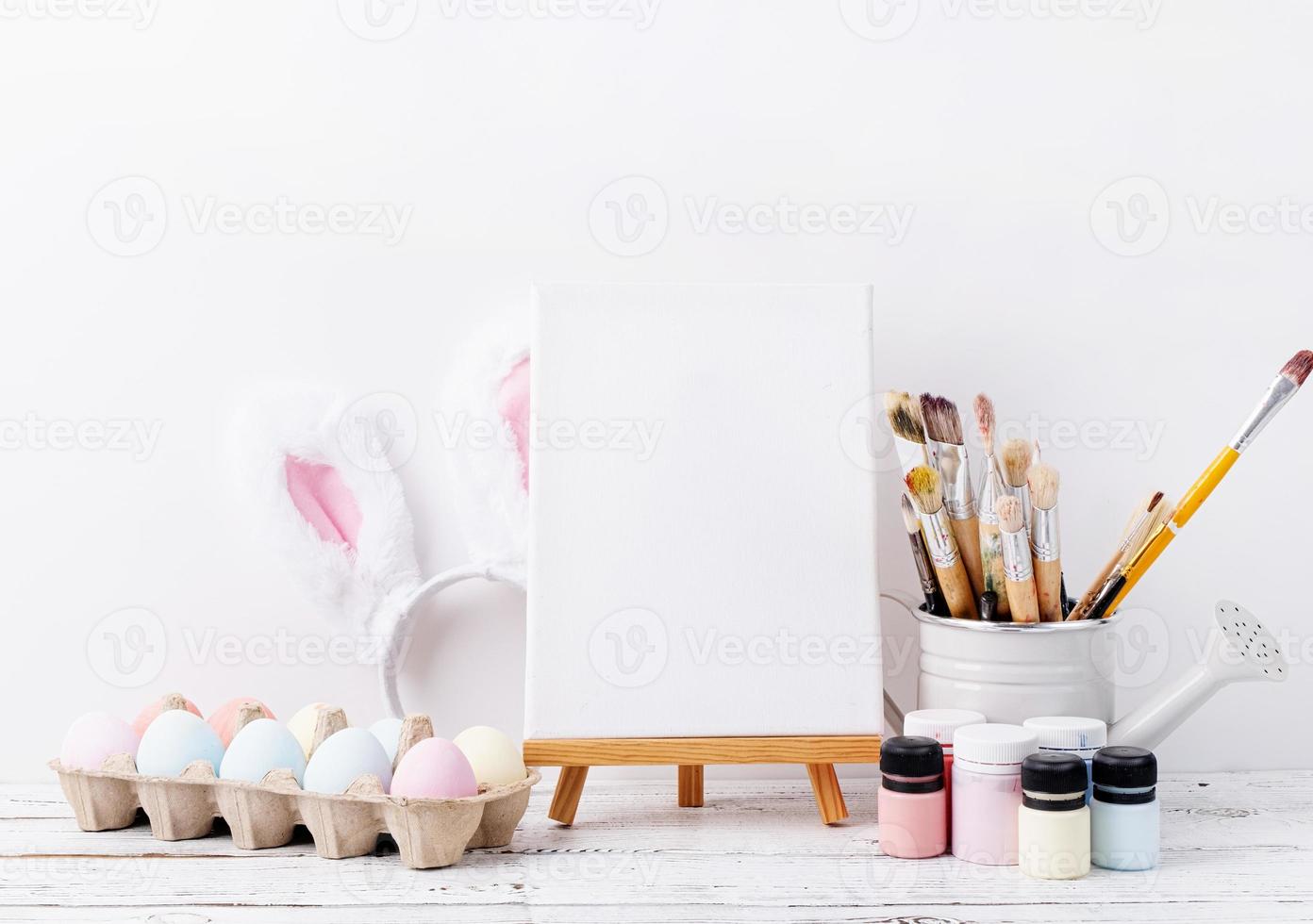 Pastel colored Easter eggs and mimosa flowers with blank white frame for mockup design, front view on white brick wall background photo