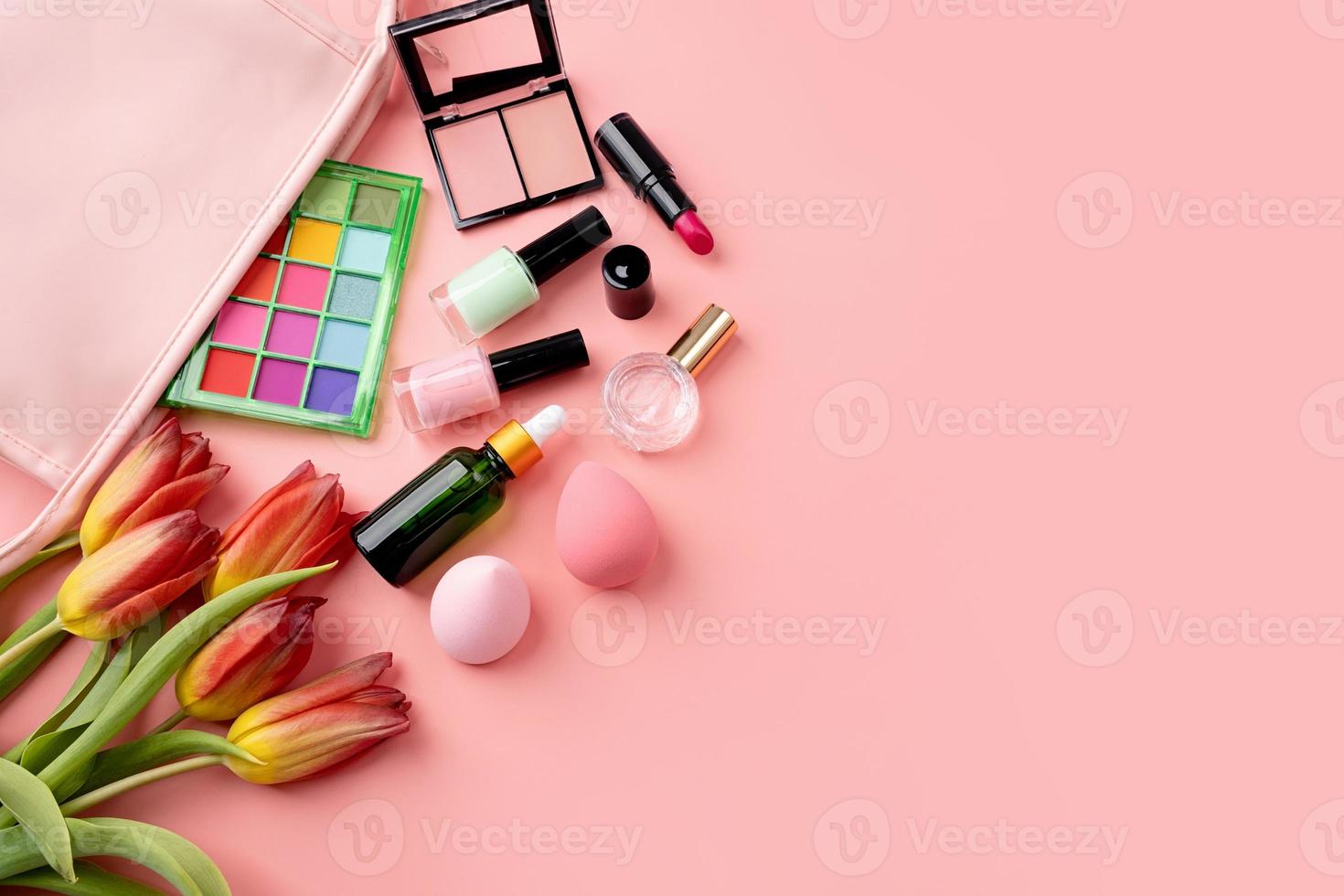 Bright summer eyeshadow palette and makeup products in pink cosmetic bag on pink background photo