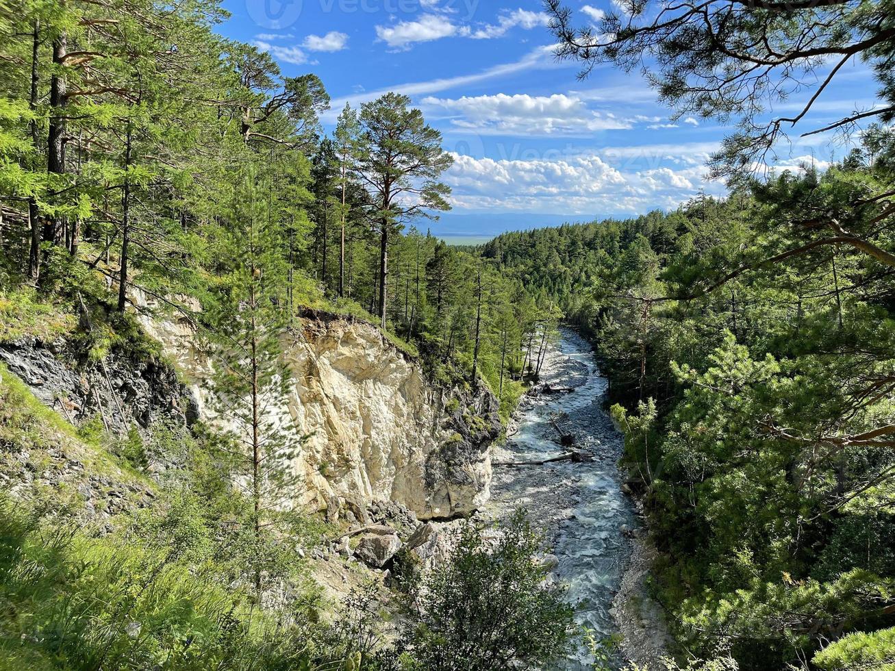 Mountain river flowing in a valley between a forest and a high cliff, Buryatia, Russia photo