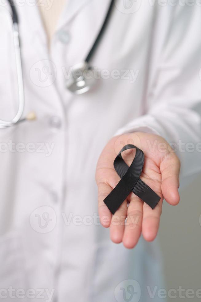 Melanoma and skin cancer, Vaccine injury awareness month and rest in peace concepts. doctor holding black Ribbon photo