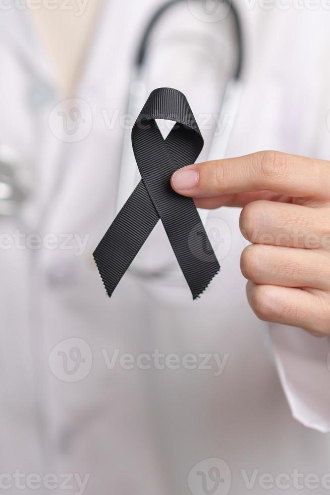 Melanoma and skin cancer, Vaccine injury awareness month and rest in peace concepts. doctor holding black Ribbon photo