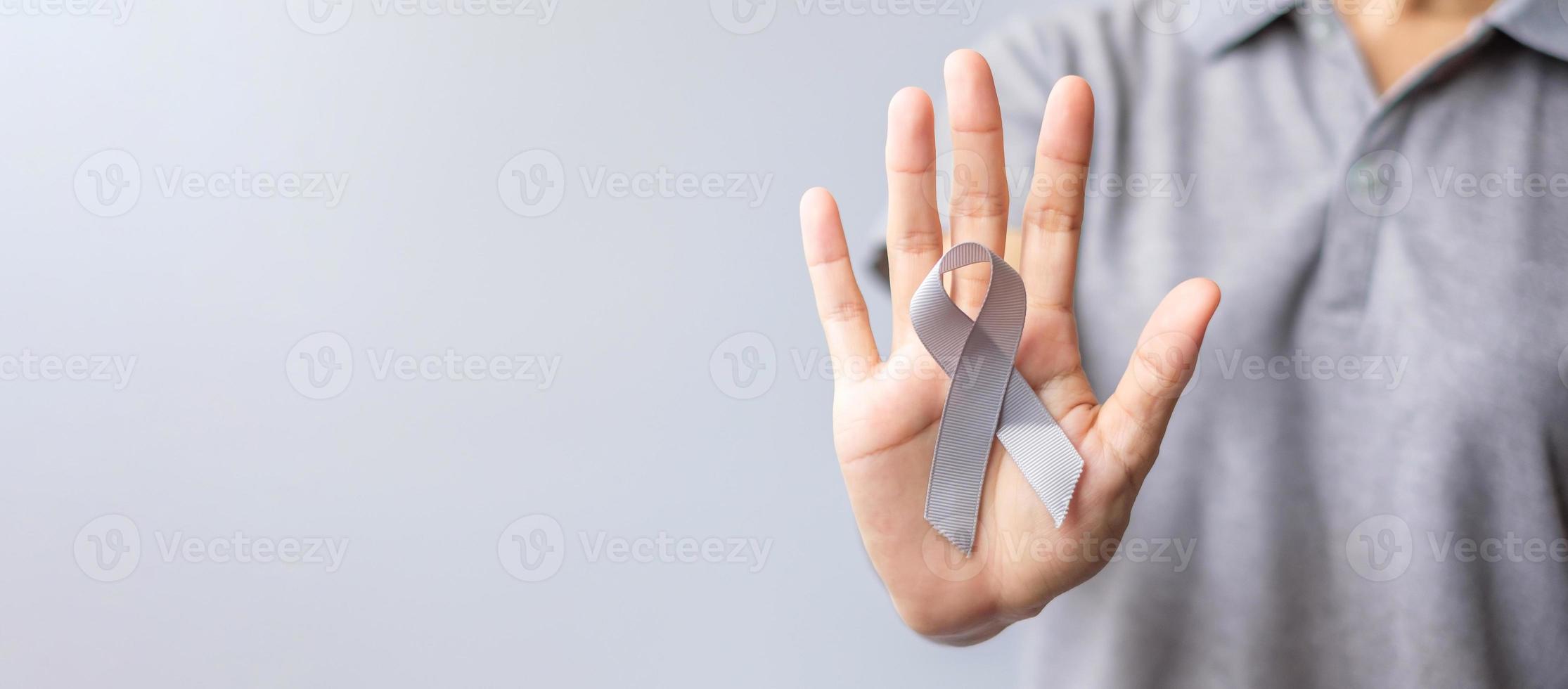 cerebro cáncer conciencia mes, mujer mano participación gris color cinta para secundario personas vida. cuidado de la salud y mundo cáncer día concepto foto