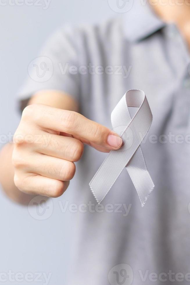 Brain Cancer Awareness month, woman hand holding grey color Ribbon for supporting people life. Healthcare and World cancer day concept photo