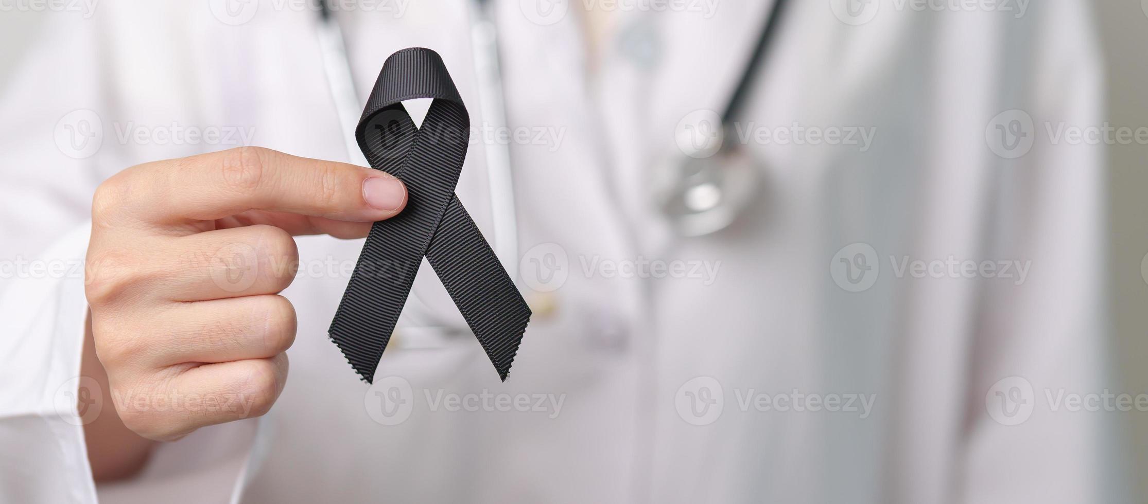 Melanoma and skin cancer, Vaccine injury awareness month and rest in peace concepts. doctor holding black Ribbon photo