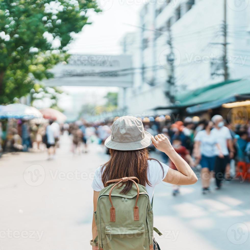 woman traveler visiting in Bangkok, Tourist with backpack and hat sightseeing in Chatuchak Weekend Market, landmark and popular attractions in Bangkok, Thailand. Travel in Southeast Asia concept photo
