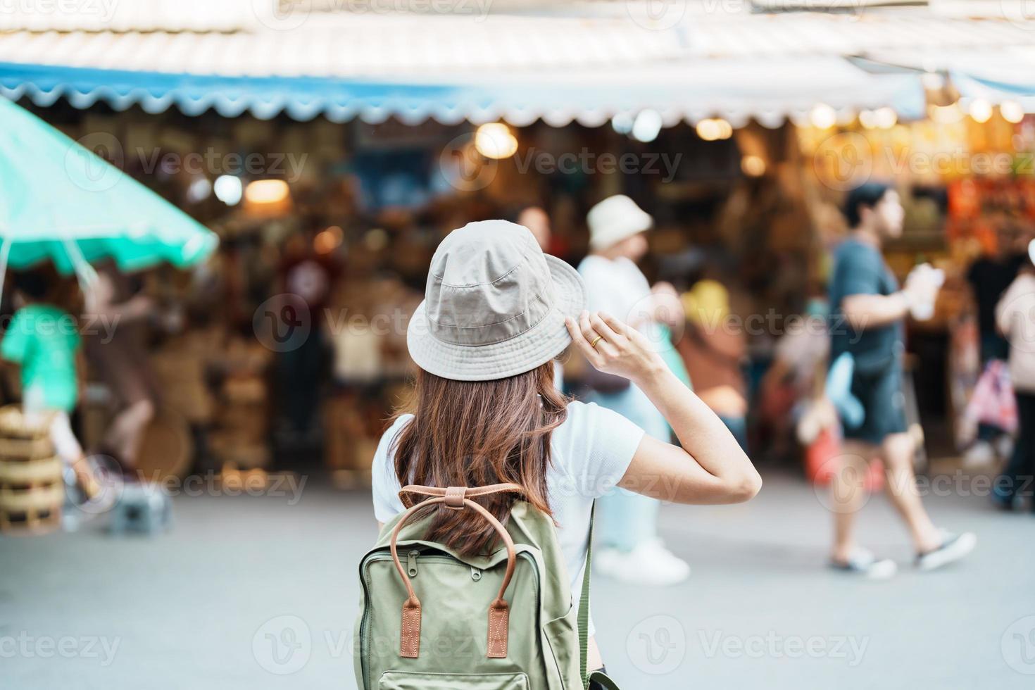 woman traveler visiting in Bangkok, Tourist with backpack and hat sightseeing in Chatuchak Weekend Market, landmark and popular attractions in Bangkok, Thailand. Travel in Southeast Asia concept photo
