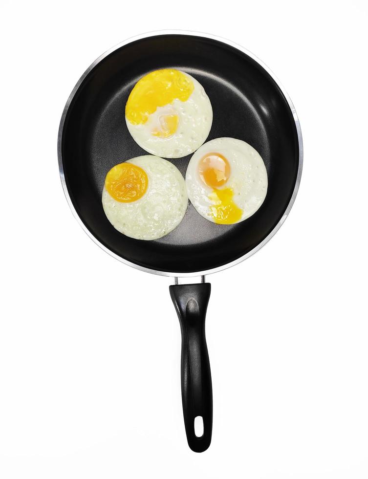 sunny side up eggs on a black pan isolated in white background photo