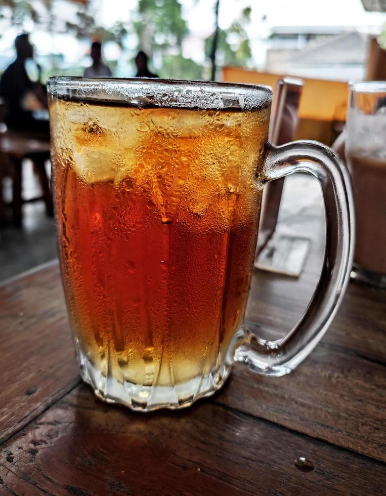 A glass of sweet cold iced tea on wooden table photo