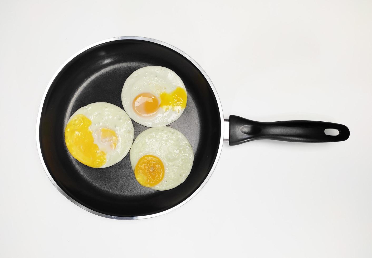 sunny side up eggs on a black pan isolated in white background photo