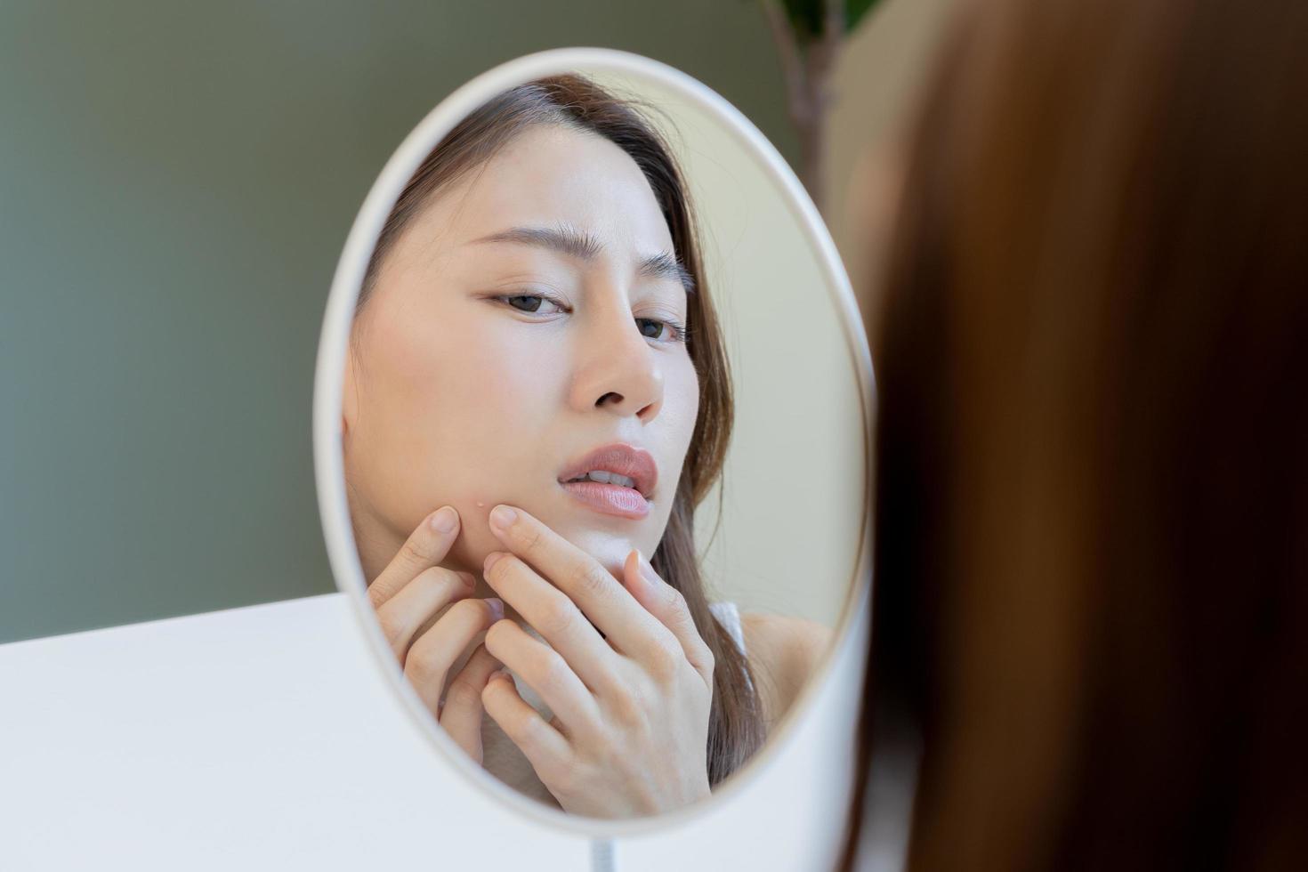 dermatología, pubertad asiático joven mujer, niña mirando dentro espejo, alergia cuando vestir máscara y cosmético, espectáculo apretando espinilla Mancha para quitando desde cara.belleza cuidado desde piel problema por acné tratamiento foto