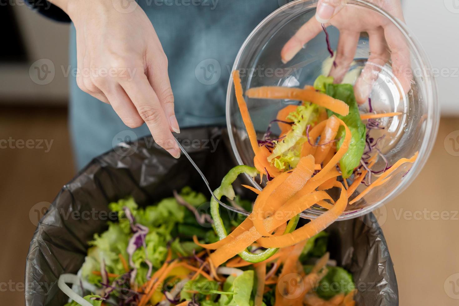 Compost the kitchen waste, recycling, organic meal asian young household woman scraping, throwing food leftovers into the garbage, trash bin from vegetable. Environmentally responsible, ecology. photo