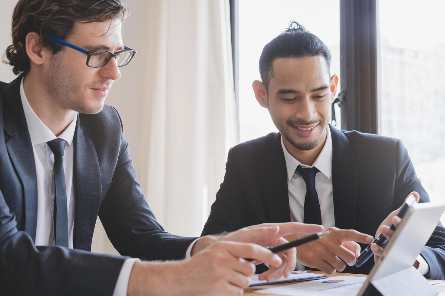 Business meeting, two caucasian, asian yong group man brainstorm analyzing on graph data of cost plan or document, paperwork and discussing in board room on table. People working conference room. photo