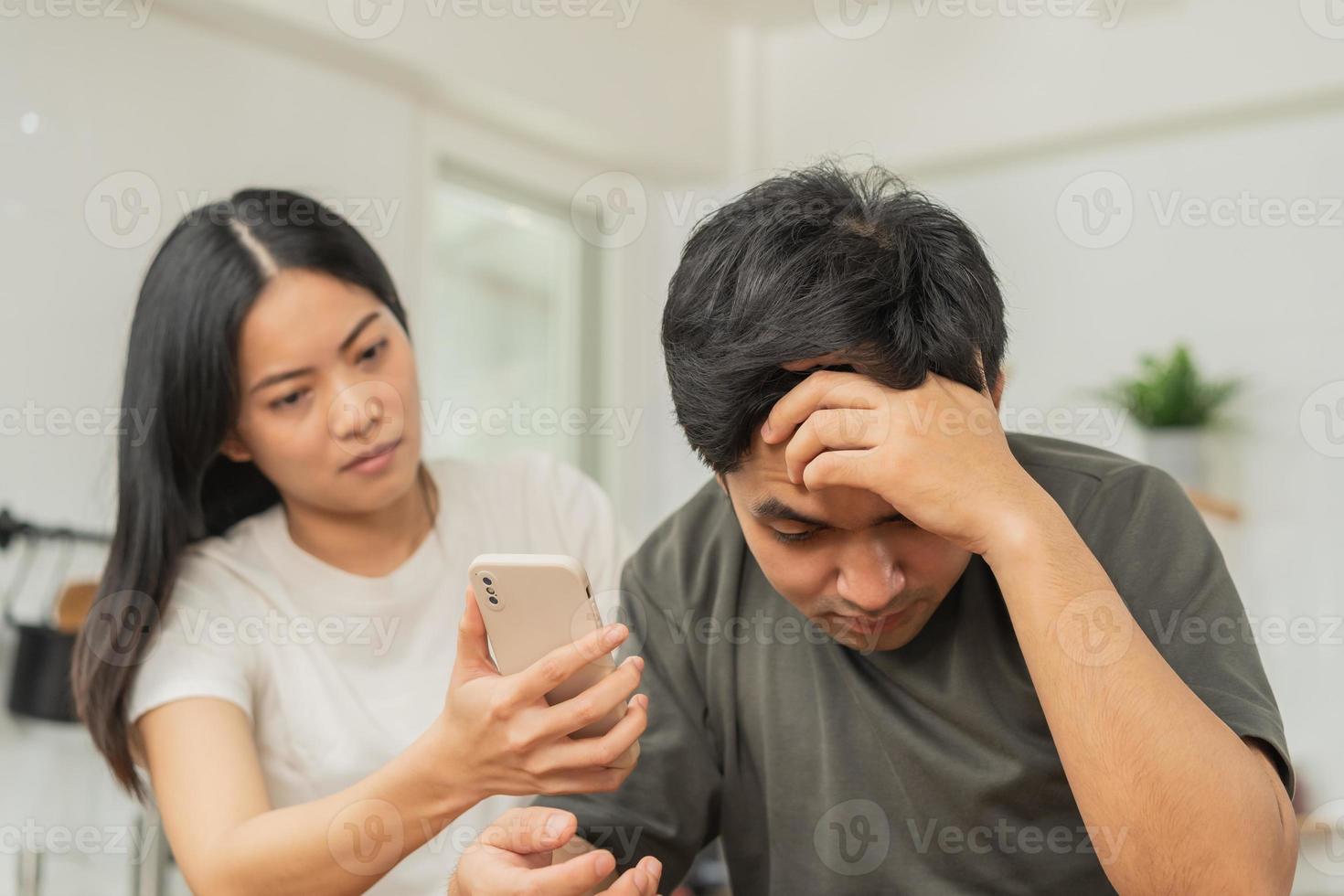 infidelidad, sospecha asiático joven Pareja amor lucha relación, esposa participación Teléfono móvil, teléfono inteligente engañando en teléfono, regaño marido acerca de desconfianza, desconfianza y celos cuando sentado a hogar. foto