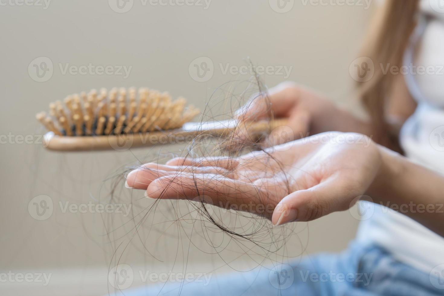 grave, preocupado asiático joven mujer, niña participación peine, espectáculo su cepillo para el pelo con largo pérdida pelo problema después cepillado, pelo otoño fuera problema. salud cuidado, belleza con Copiar espacio en blanco antecedentes. foto